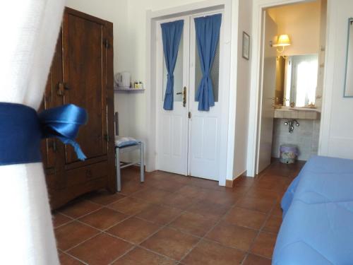 a bedroom with a bed and a door with blue curtains at B&B Il Gatto Pescatore in Stintino