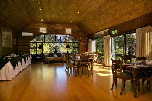 una sala da pranzo con pavimenti in legno, tavoli e sedie di Tongariro Lodge a Turangi