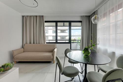 uma sala de estar com uma mesa e cadeiras e um sofá em DOKI Apartments by Blue Mandarin em Gdansk
