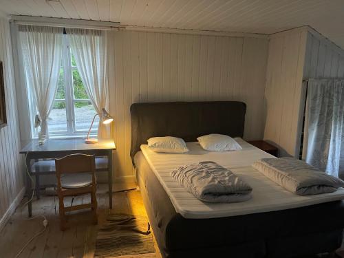 Un dormitorio con una cama y un escritorio y una ventana. en Village Cottage In The High Coast Area, en Bålsjö