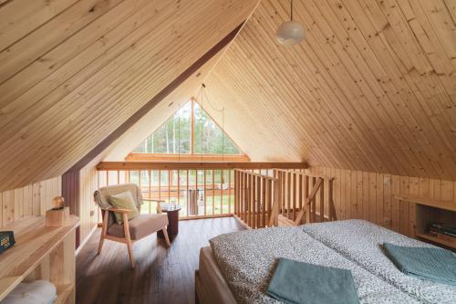 a attic bedroom with a bed and a window at Miło las widzieć in Ciwoniuki