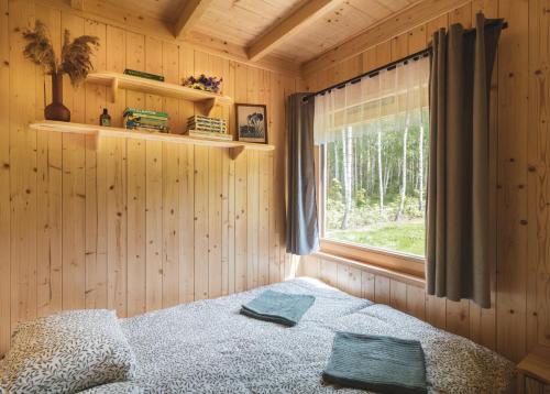a bedroom with a bed and a window in a cabin at Miło las widzieć in Ciwoniuki