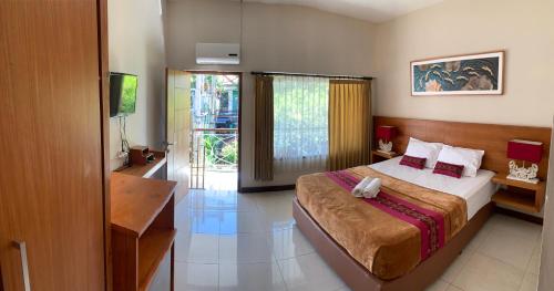 a bedroom with a bed and a desk and a television at Kuta Suci Guesthouse in Kuta