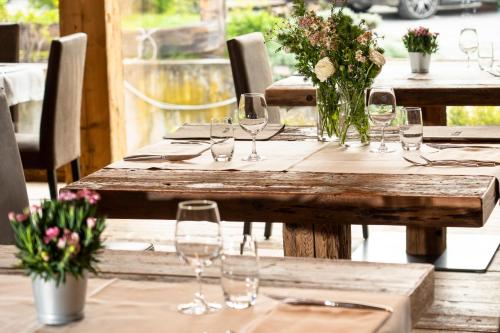 uma mesa de madeira com copos de vinho e flores em Agriturismo Rini em Bormio