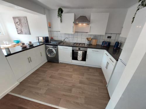 a kitchen with white cabinets and a washer and dryer at Perfect Cowes retreat with Hot Tub in Cowes