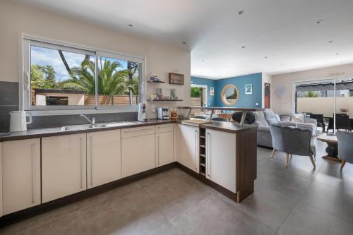 une cuisine avec des armoires blanches et un salon dans l'établissement Piscine ! Maison pour 9, à Saint-Nazaire