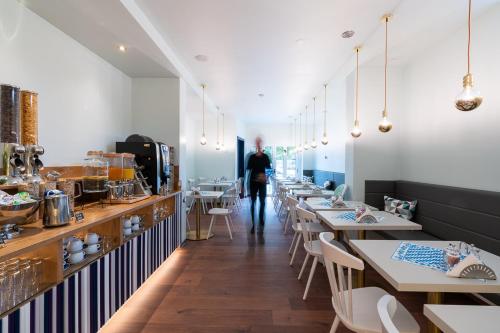 a restaurant with tables and a person walking in the distance at Das Schreder Hotel in Munich