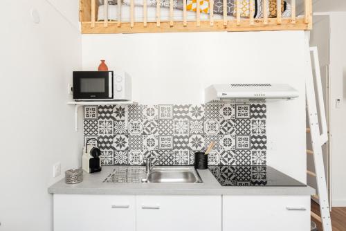 une cuisine avec un évier et un micro-ondes dans l'établissement MontSéjour - Studio Climatisé entre Gare & Cité, à Carcassonne