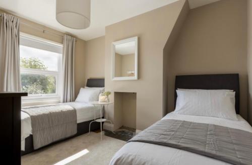 a bedroom with two beds and a mirror and a window at Fallow Cottage in Lyndhurst