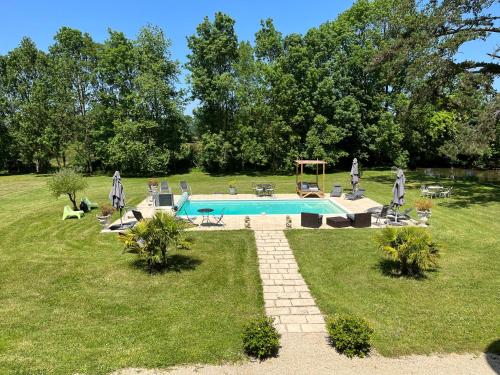 una piscina en un patio de césped con árboles y un campo en Chateau Du Four De Vaux en Varennes Vauzelles