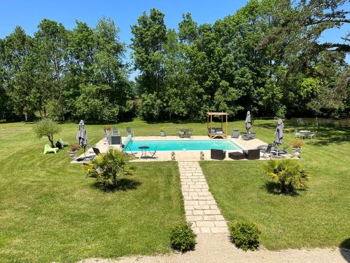 una piscina en un patio de césped con árboles y un campo en Chateau Du Four De Vaux, en Varennes Vauzelles