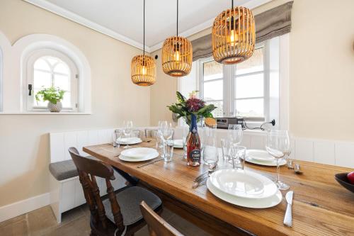 a dining room with a wooden table and chandeliers at Ferienhaus Miarwuefki in Rantum