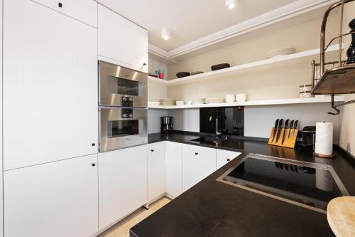 a kitchen with white cabinets and black countertops at Ferienhaus Miarwuefki in Rantum