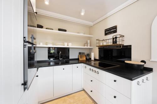 a kitchen with white cabinets and black counter tops at Ferienhaus Miarwuefki in Rantum
