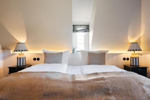 a bedroom with a large bed with two lamps at Ferienhaus Miarwuefki in Rantum