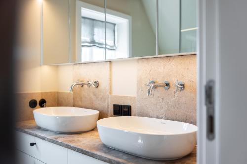 a bathroom with two sinks and a mirror at Ferienhaus Miarwuefki in Rantum