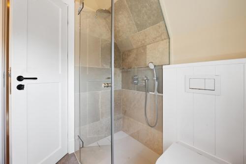 a bathroom with a shower with a glass door at Ferienhaus Miarwuefki in Rantum