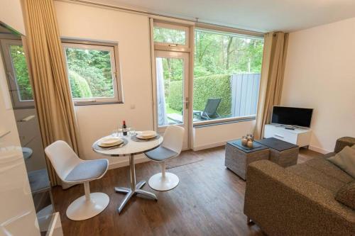 a living room with a table and chairs and a couch at Heerlijk vakantiehuisje op rustig Natuurpark in Otterlo