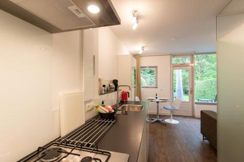 a kitchen with a stove top oven next to a table at Heerlijk vakantiehuisje op rustig Natuurpark in Otterlo
