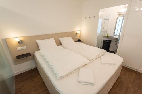 1 cama blanca con almohadas blancas en una habitación en Heerlijk vakantiehuisje op rustig Natuurpark en Otterlo