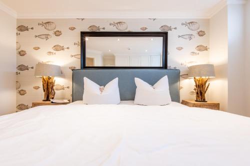 a bedroom with a large white bed with two lamps at Haus Bötticher Straße Whg 01 in Westerland (Sylt)