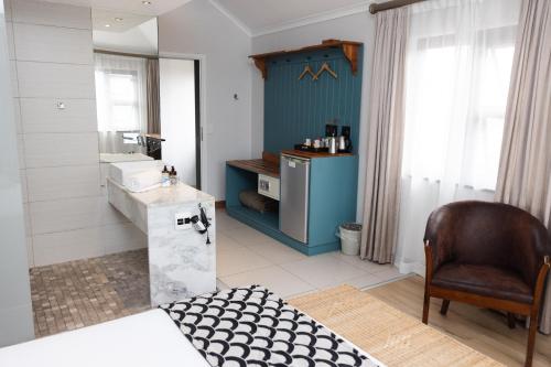 łazienka z łóżkiem, umywalką i krzesłem w obiekcie Swakopmund Sands w mieście Swakopmund