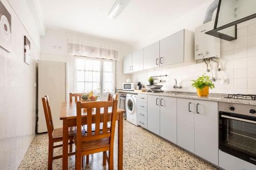 uma cozinha com armários brancos e uma mesa e cadeiras em Casa Alto da Serra Sesimbra em Sesimbra