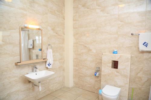a bathroom with a sink and a toilet and a mirror at Executive Suites in Kigali