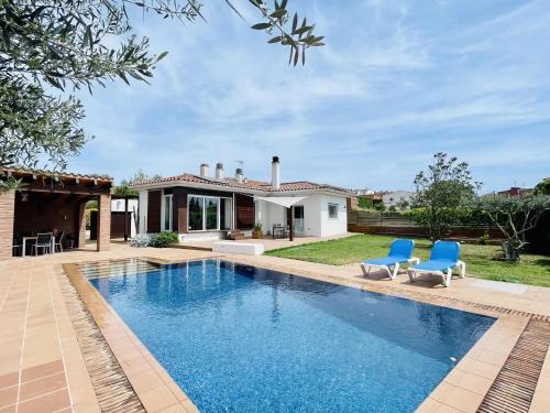 a swimming pool with two blue chairs and a house at Casa Albons by Costabravaway in Albóns