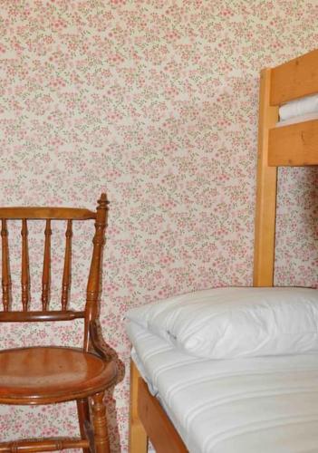 a bedroom with a bed and a wooden chair at Stuga i vassemåla in Vimmerby