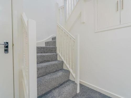 eine Treppe in einem Haus mit weißen Wänden und grauem Teppich in der Unterkunft Baltic Dockside Apartment, Free Parking in Liverpool