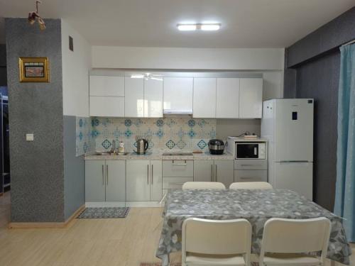 a kitchen with a table and chairs and a white refrigerator at OUNT-Central location, spacious, cozy and secure in Ulaanbaatar