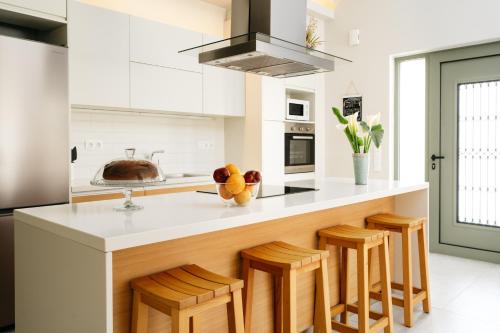 a kitchen with a counter with wooden stools at Eumelia Iconic Villa, with Heated Pool & Whirlpool, By ThinkVilla in Asigonía