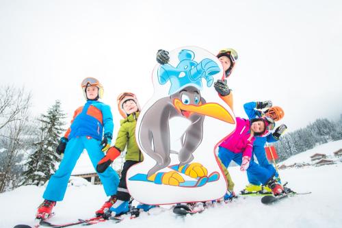 a group of children on skis standing next to a penguin sign at Apart Hotel Alpenhof Werfenweng in Werfenweng