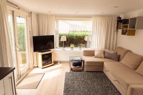 a living room with a couch and a flat screen tv at Knus huisje op kindvriendelijk park met zwembad in Otterlo