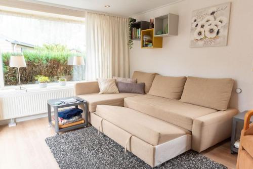 a living room with a couch and a table at Knus huisje op kindvriendelijk park met zwembad in Otterlo