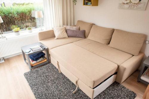 a brown couch in a living room with a window at Knus huisje op kindvriendelijk park met zwembad in Otterlo