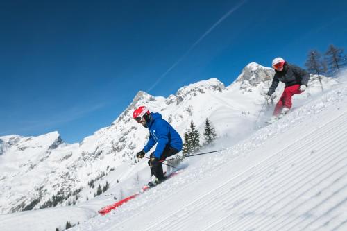 two people skiing down a snow covered mountain at Apart Hotel Alpenhof Werfenweng in Werfenweng