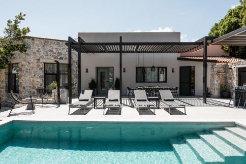 a patio with chairs and a pool in front of a house at Eumelia Iconic Villa, with Heated Pool & Whirlpool, By ThinkVilla in Asigonía