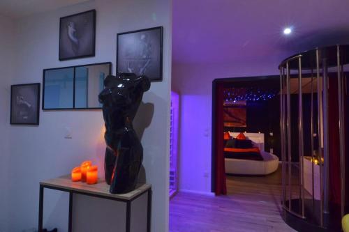 une pièce avec une statue sur une table avec des bougies orange dans l'établissement L'indécente - Love Room Studios, à Longeville-lès-Saint-Avold