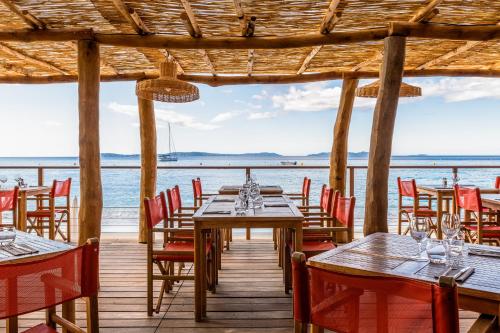 a restaurant with tables and chairs and the ocean at Hôtel Le Bailli De Suffren in Rayol-Canadel-sur-Mer
