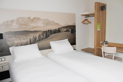 Grésy-sur-AixにあるB&B HOTEL Aix-les-Bainsのベッドルーム1室(ベッド2台付)が備わります。壁には絵画が飾られています。