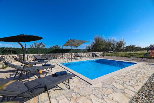 una piscina con sillas y sombrilla en Villa Niko Your vacation starts here en Rudine