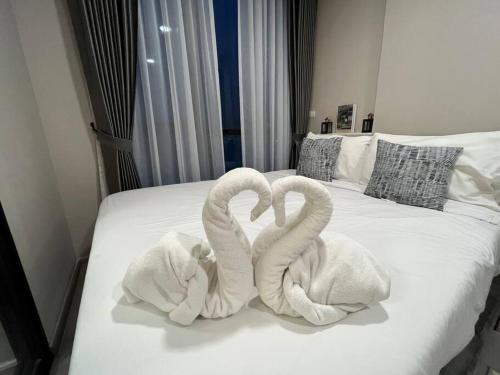 Dos cisnes de toalla sentados encima de una cama en Maxxi Prime Ratchada - Sutthisan near JodFair Market, en Ban Na Song
