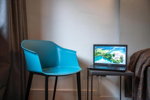 a blue chair sitting next to a laptop on a table at Hotel Ciclamino in Pietramurata