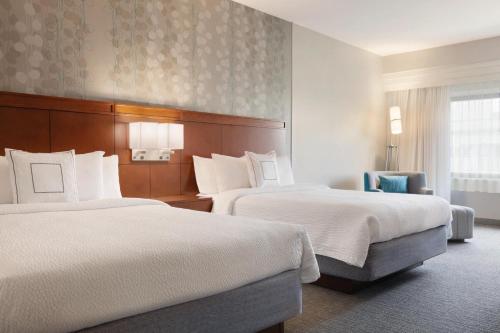 a hotel room with two beds and a chair at Courtyard Charlotte Airport North in Charlotte
