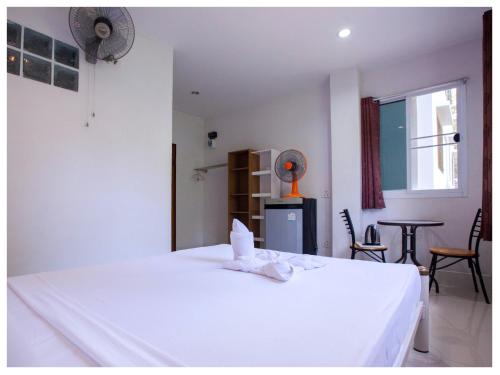 a bedroom with a white bed and a table and a window at Namhasin House in Koh Tao