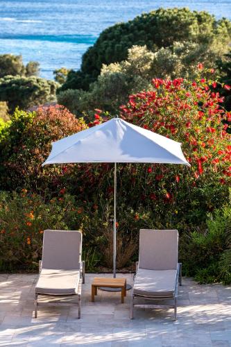 two chairs and an umbrella and a table at Les Terrasses du Bailli in Rayol-Canadel-sur-Mer