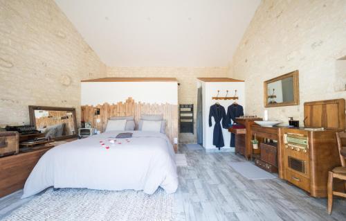 um quarto com uma grande cama branca e uma casa de banho em L'Eden chambre d'hôtes avec jacuzzi et massages em Saint-Aubin-la-Plaine