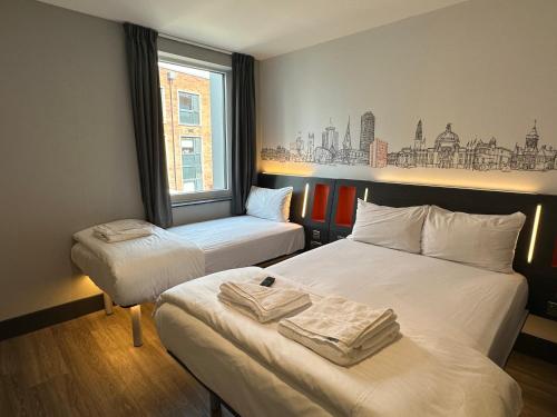 a hotel room with two beds with towels on them at easyHotel Cardiff in Cardiff